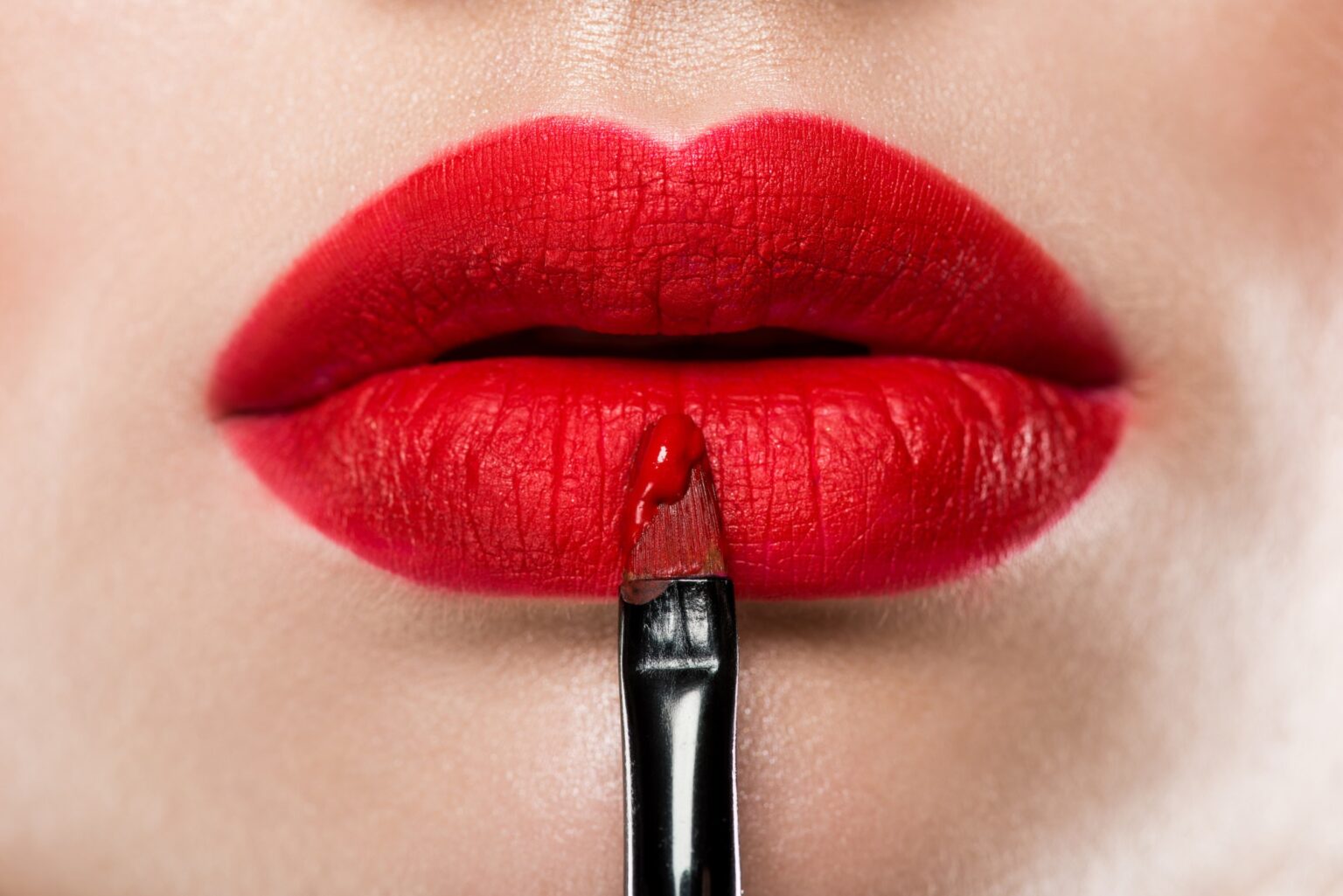 close-up-view-of-elegant-woman-applying-red-lipstick-with-cosmetic-brush.jpg
